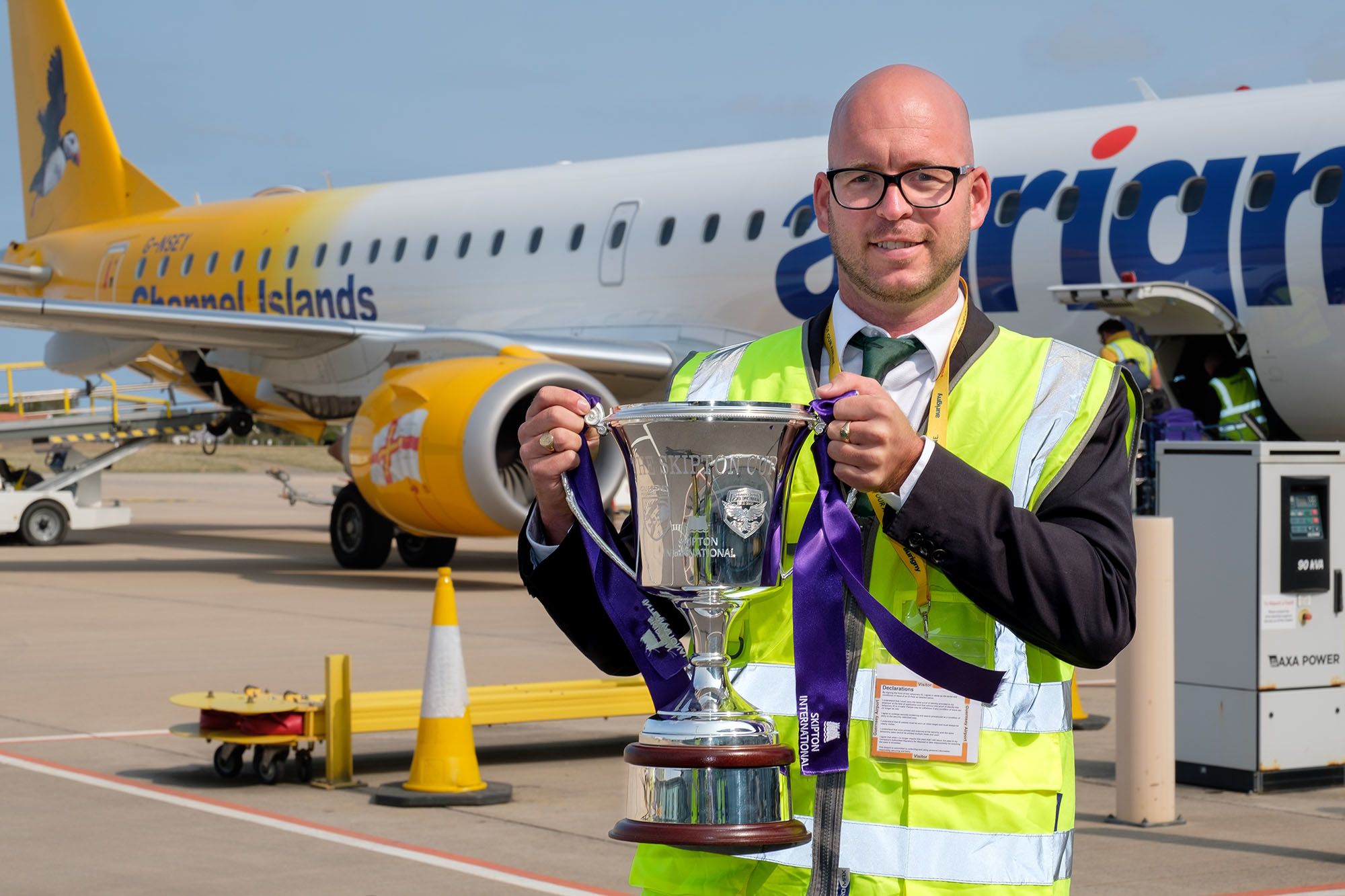 Nic Legg holds up a trophy in front of an aircraft.