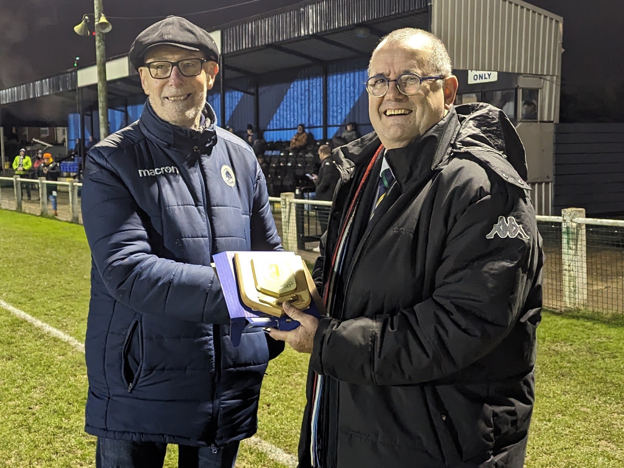 Nick Robinson presents an award on a foootball pitch.