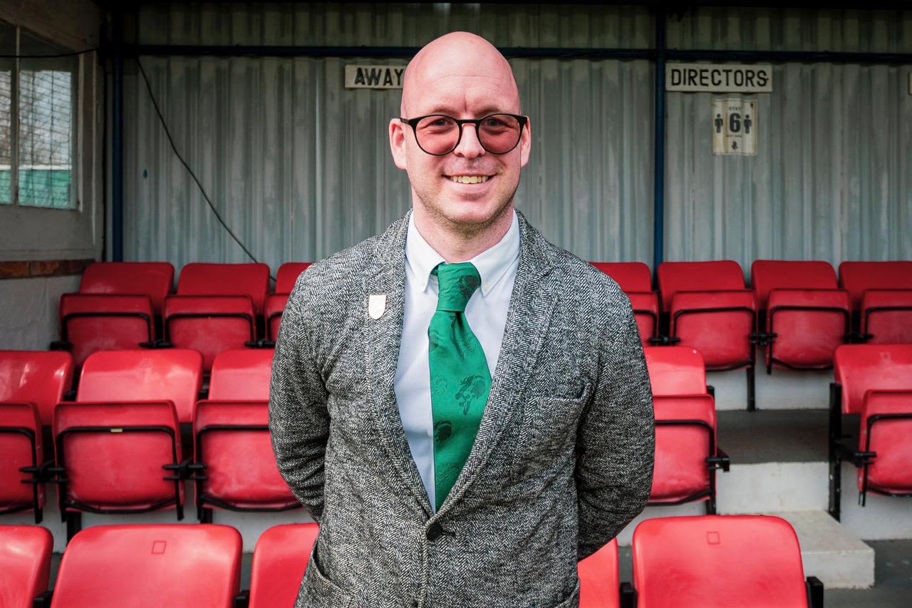 Nic Legg smiles in front of a football stand.